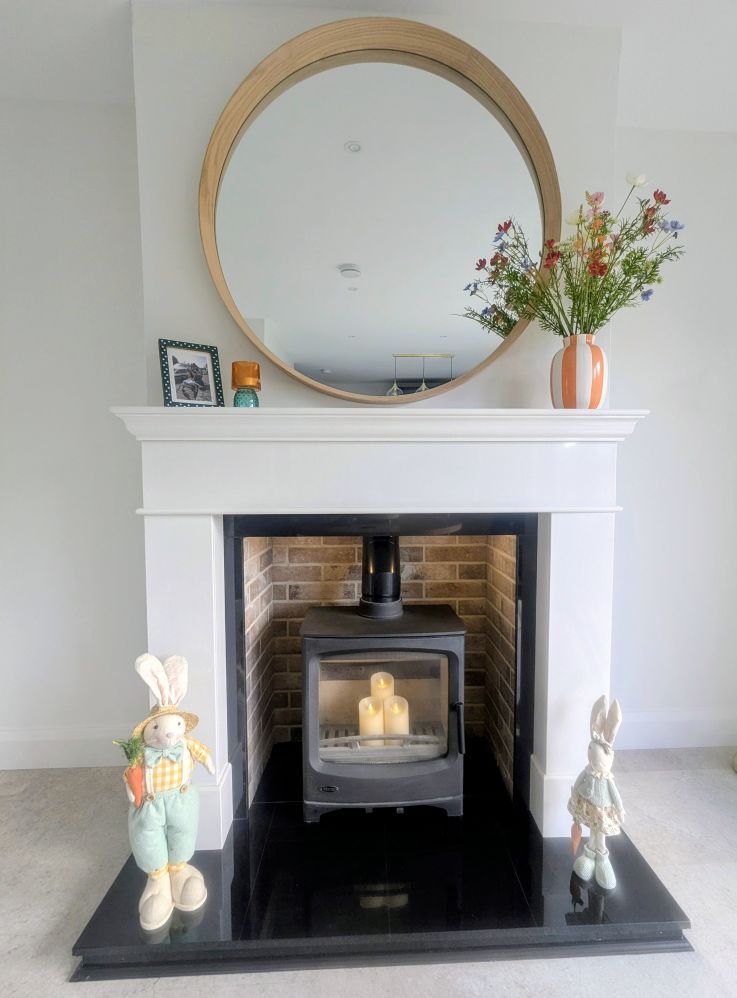 Cream mantel alcove with black stove and round mirror