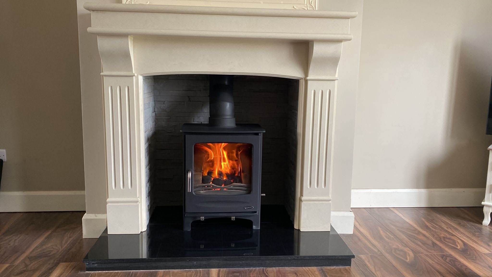 Cream fluted mantel alcove with black stove on glass hearth